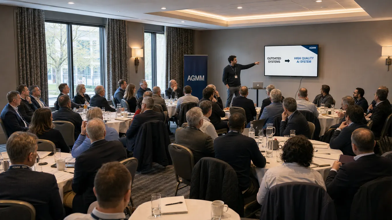 A full room of business leaders at an AGMM session, with an AGMM slide reading outdated systems, high quality AI system